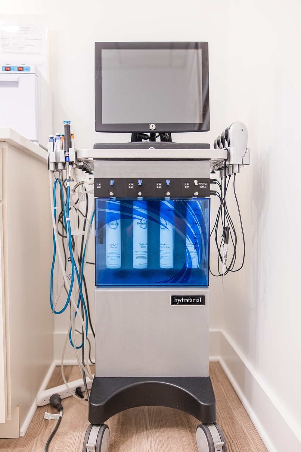 Hydrafacial machine on wheels with blue liquid.