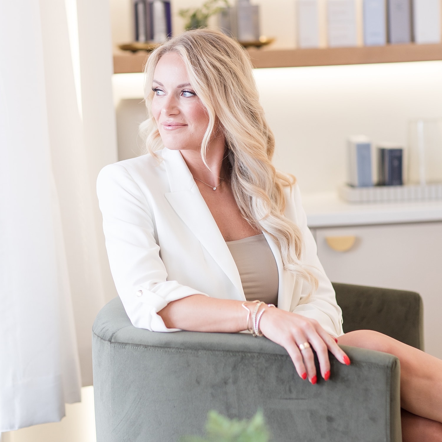 Woman in white blazer seated in modern interior.