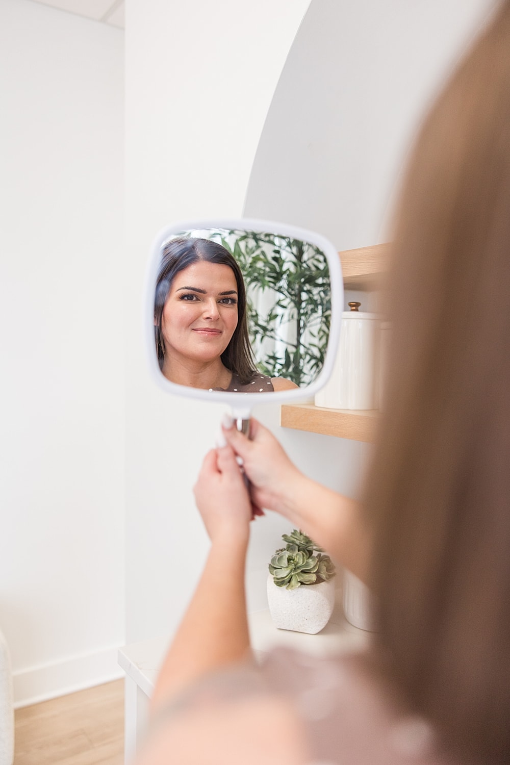 Woman looking in a handheld mirror.