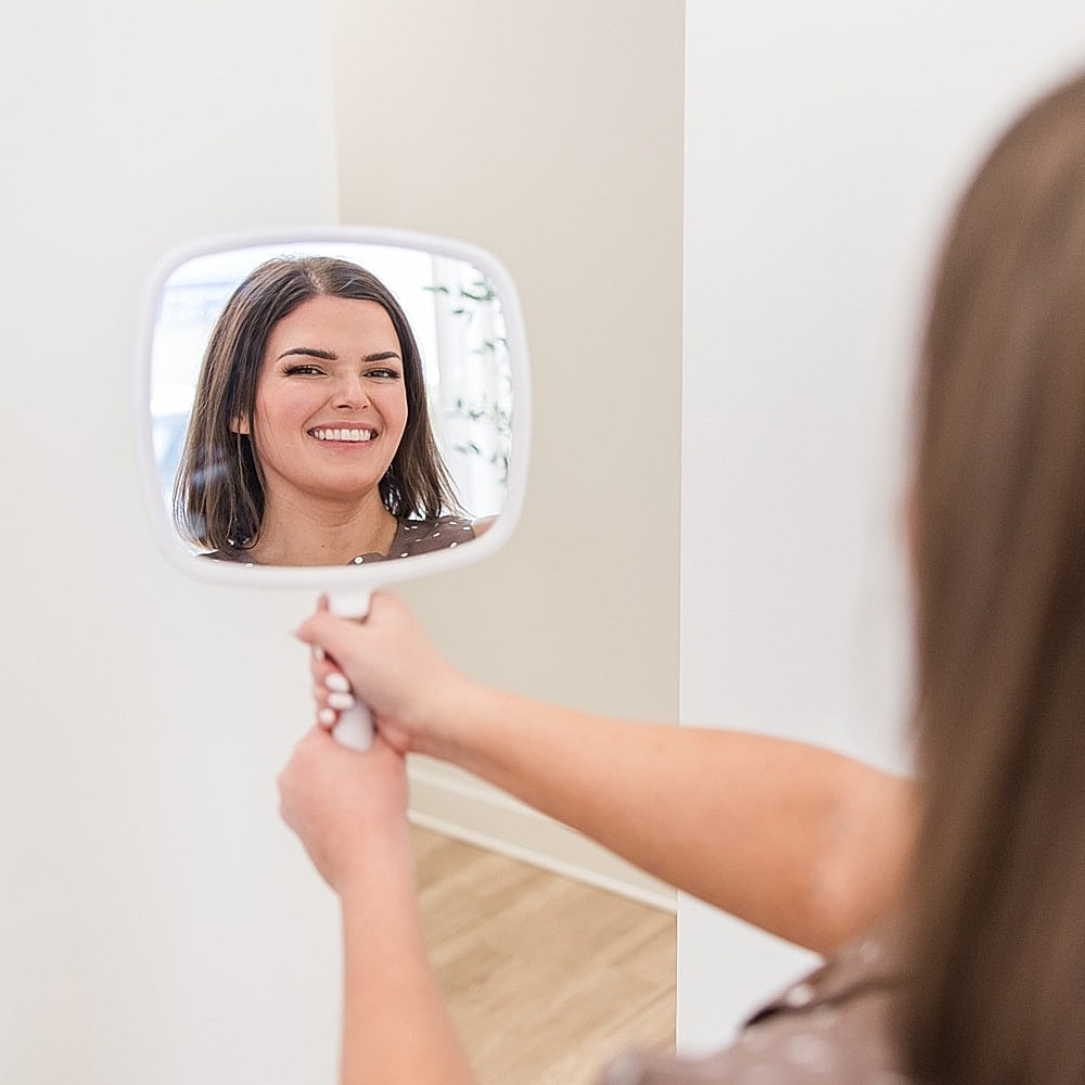 Woman smiling at herself in a mirror.