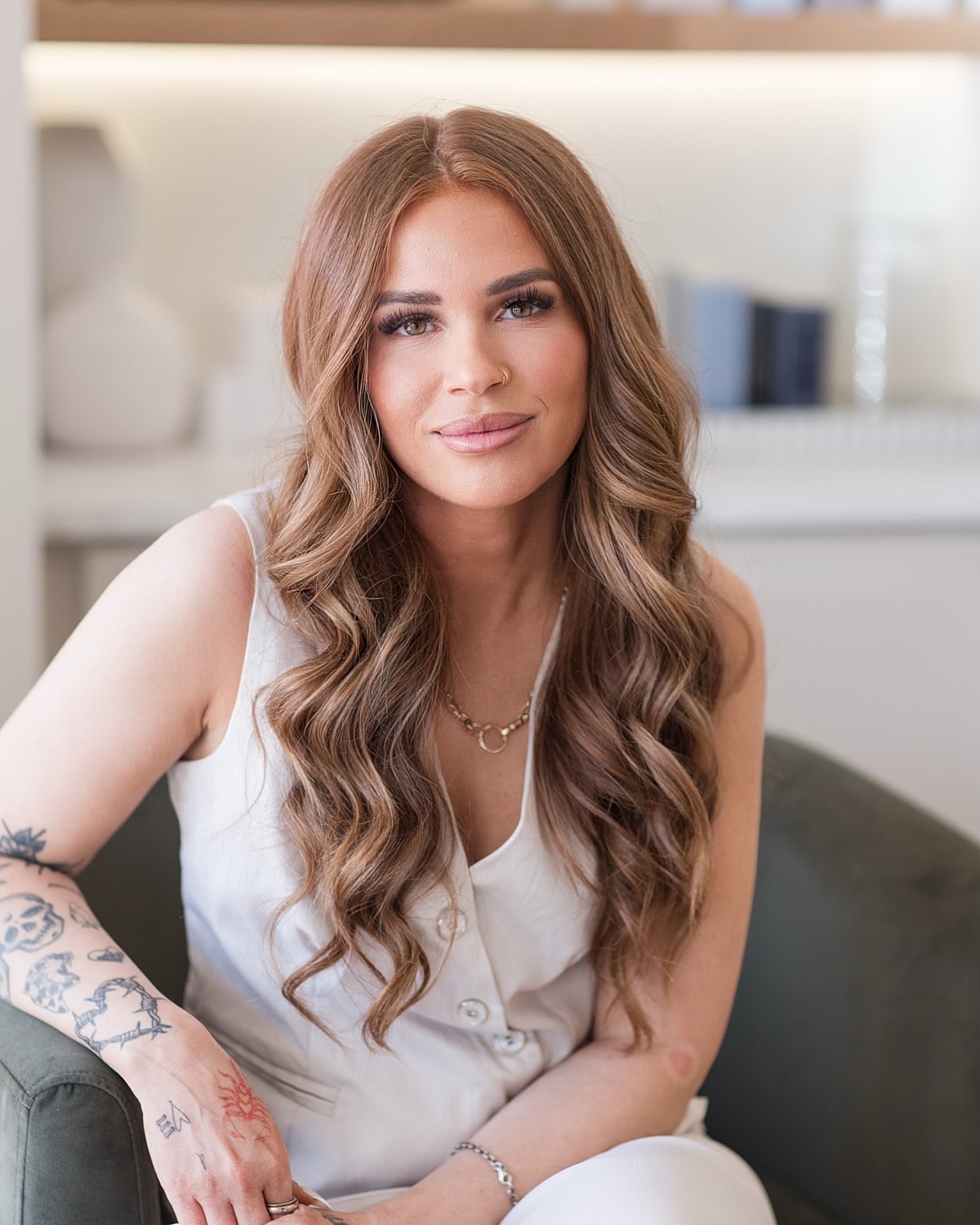 Woman with wavy hair sitting on a couch.