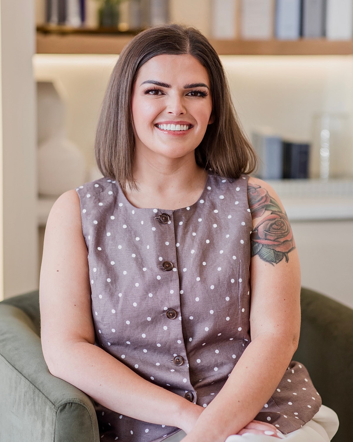 Smiling woman with short hair and polka dot top.