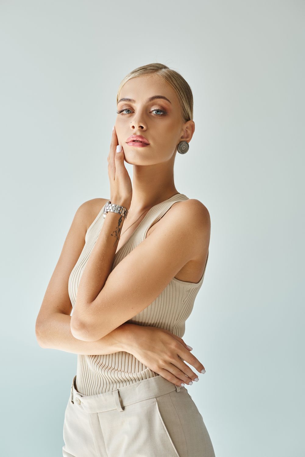 Woman in stylish attire posing elegantly against backdrop.