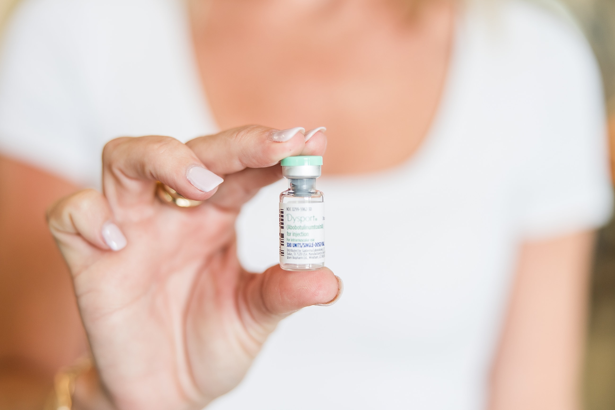 Hand holding a vial of Dysport medication.