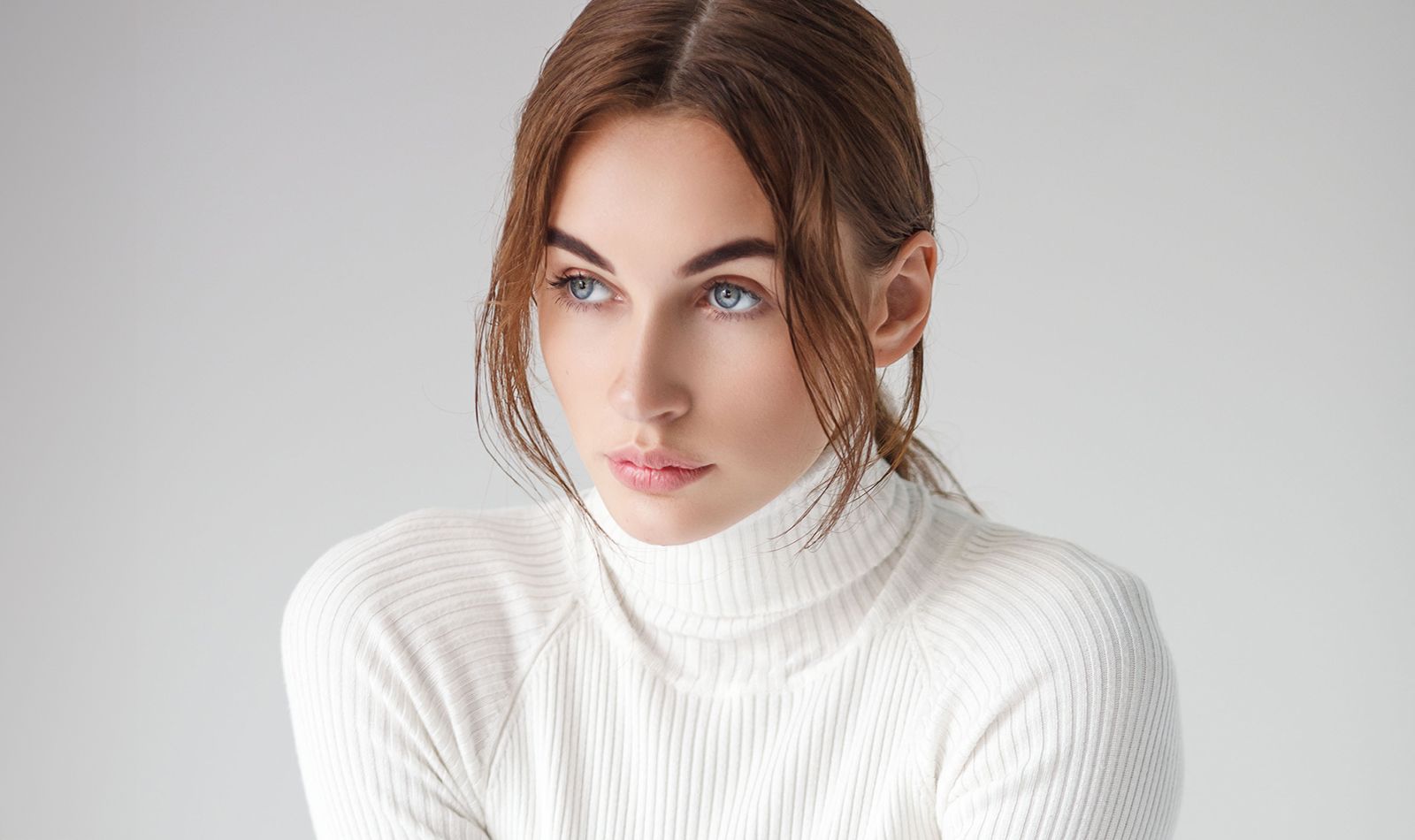 Model in a white turtleneck, thoughtful expression.
