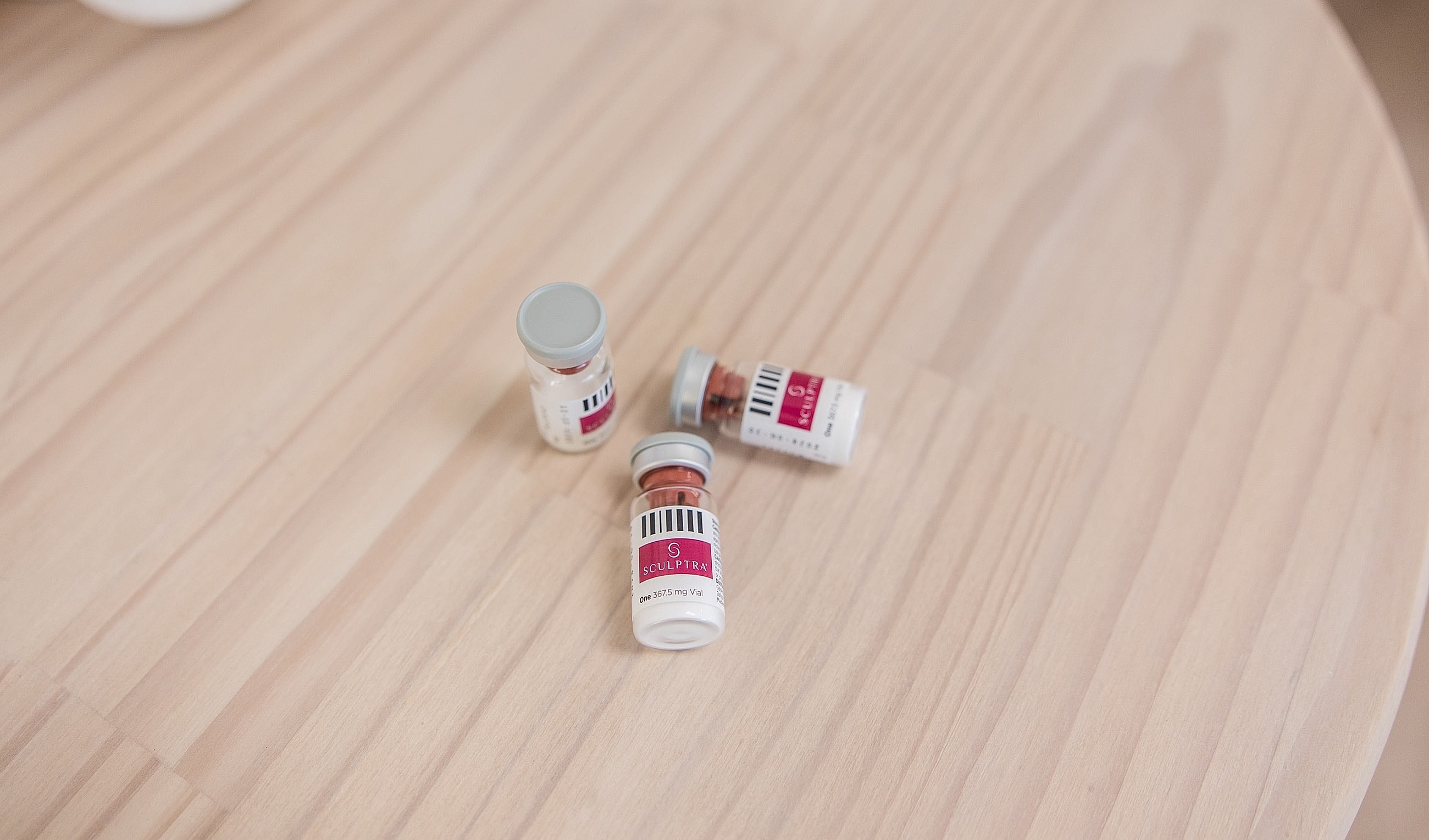 Vials of Sculptra on a wooden surface.