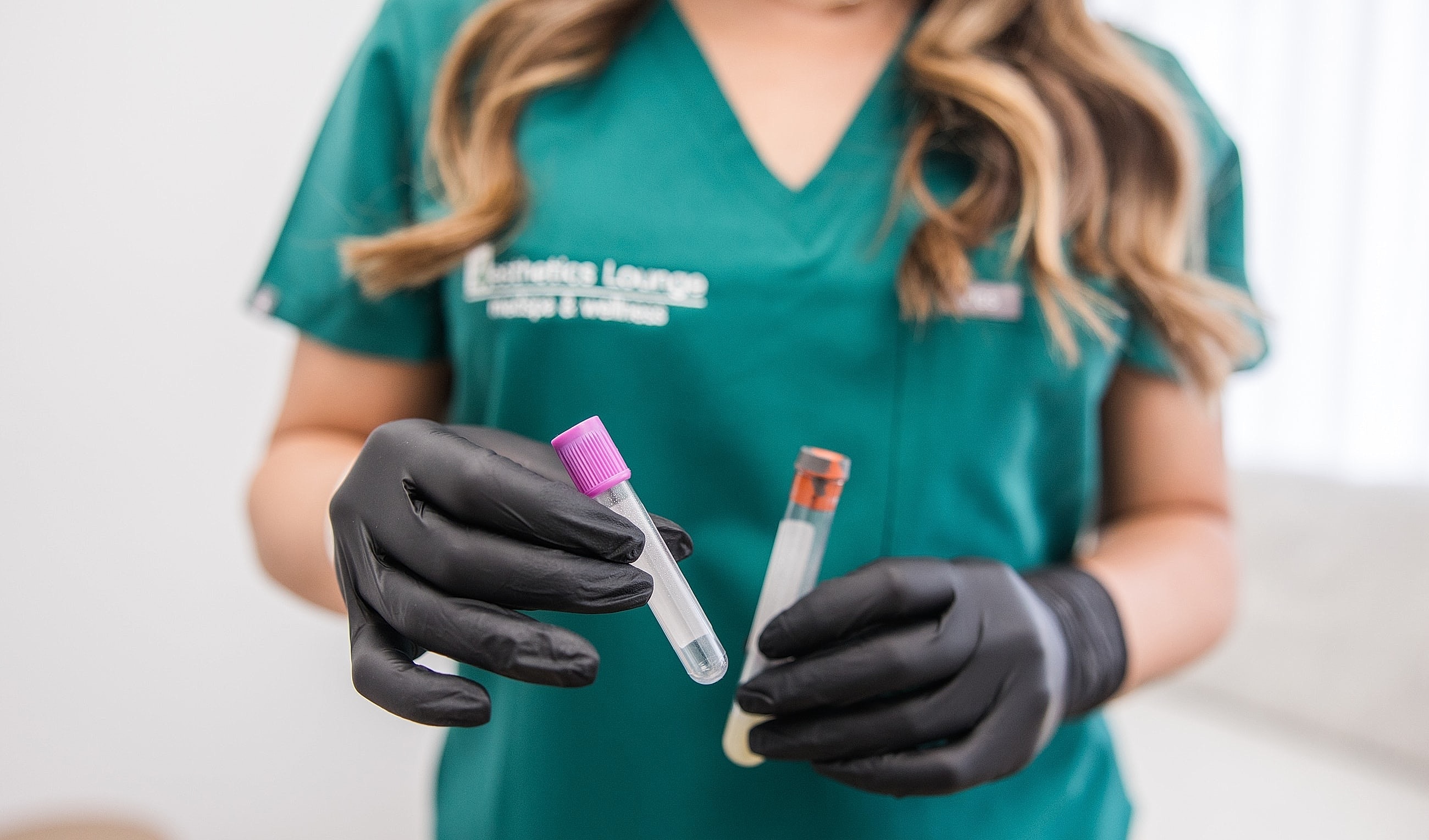 Health professional holding test tubes in gloves.