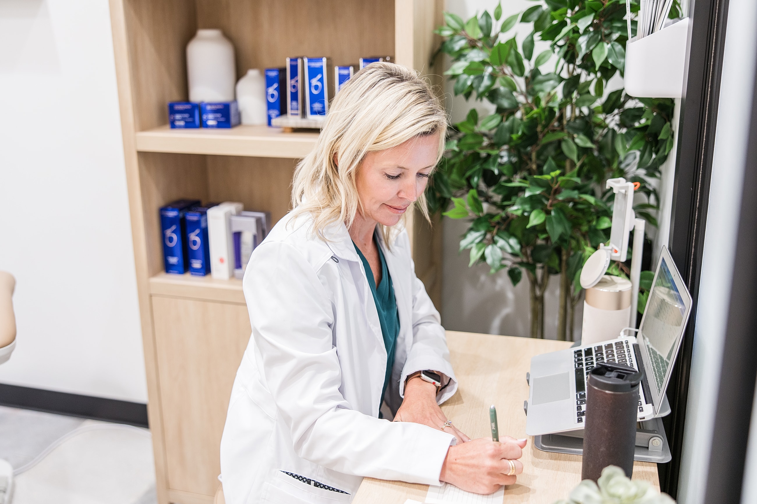Professional in lab coat writing notes at desk