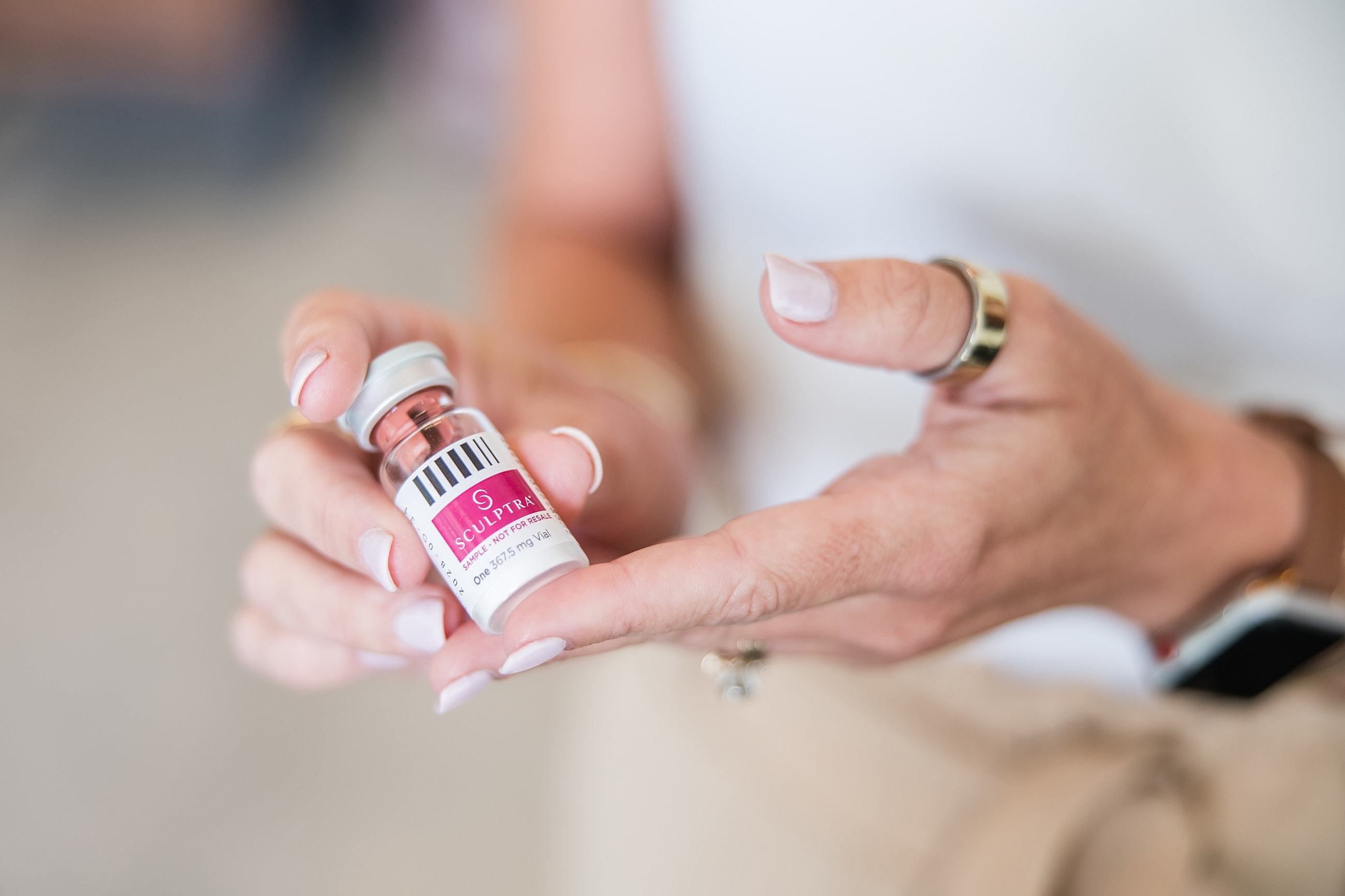 Hand holding a vial of Sculptra.